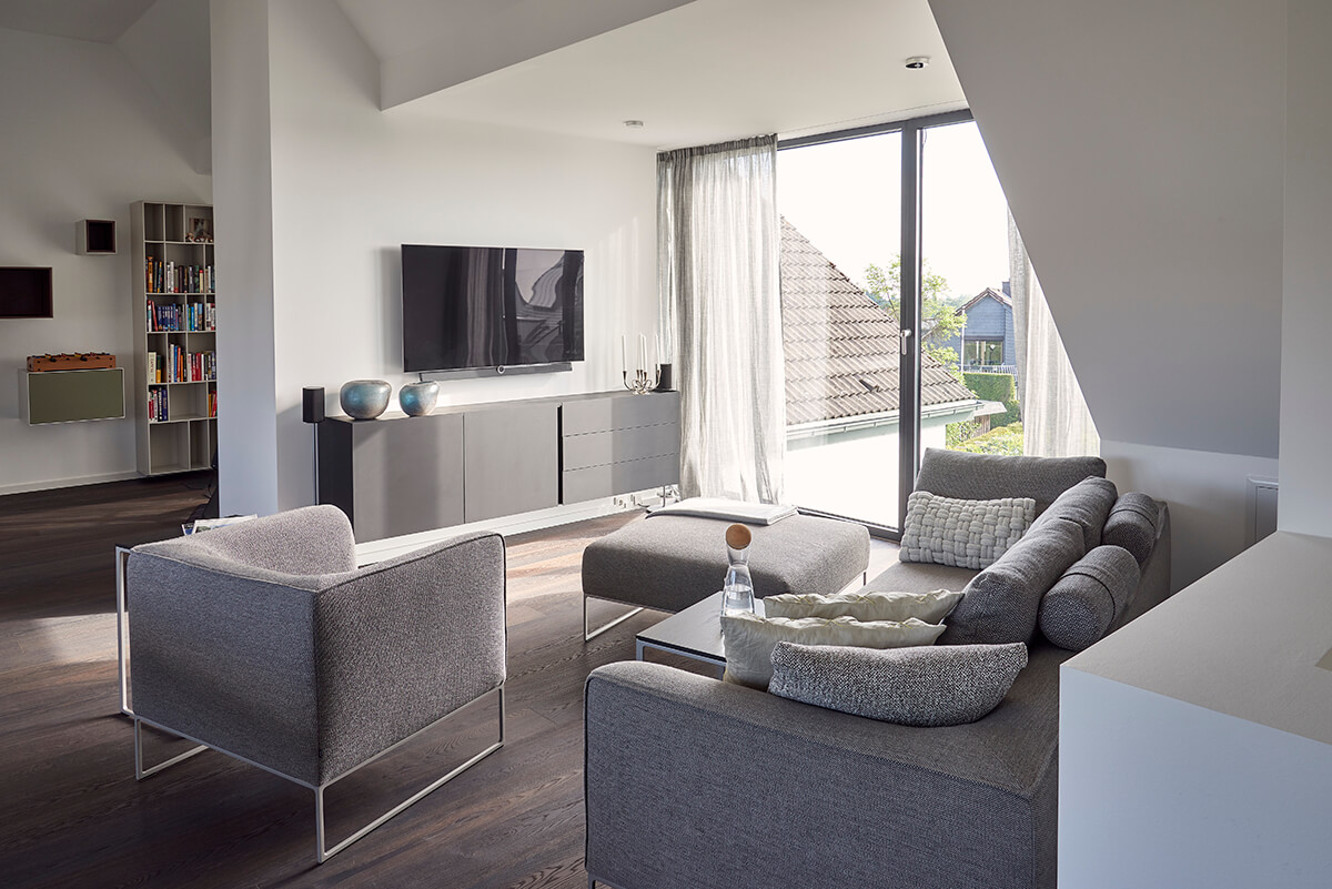 Gemütliches Raumambiente unterm Dach mit hellgrauem Designer-Sofa und -Sessel Mell von COR.