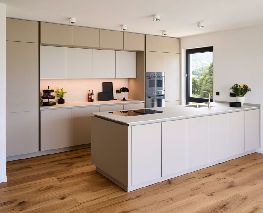 Moderne SieMatic-Küche mit grifflosen Fronten in hellem Beige, großer Kücheninsel und hochwertigen Elektrogeräten von Miele.